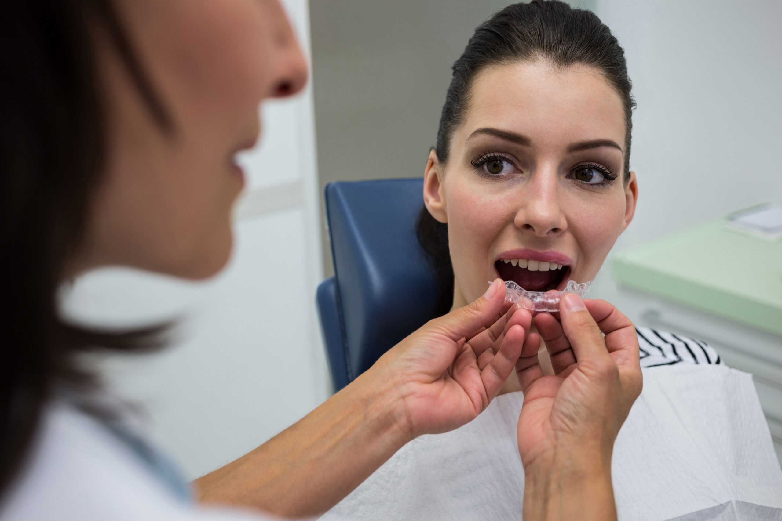 Dentist assisting a patient to wear orthodontic silicone invisible braces Dentist assisting a patient to wear orthodontic silicone invisible braces