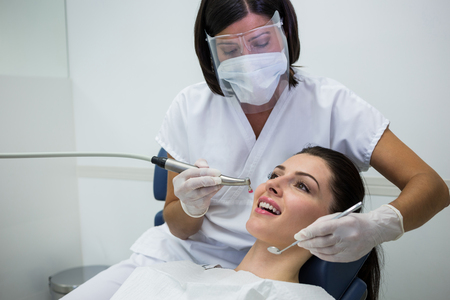 Dentist examining a female patient with tools at dental clinic Dentist examining a female patient with tools at dental clinic