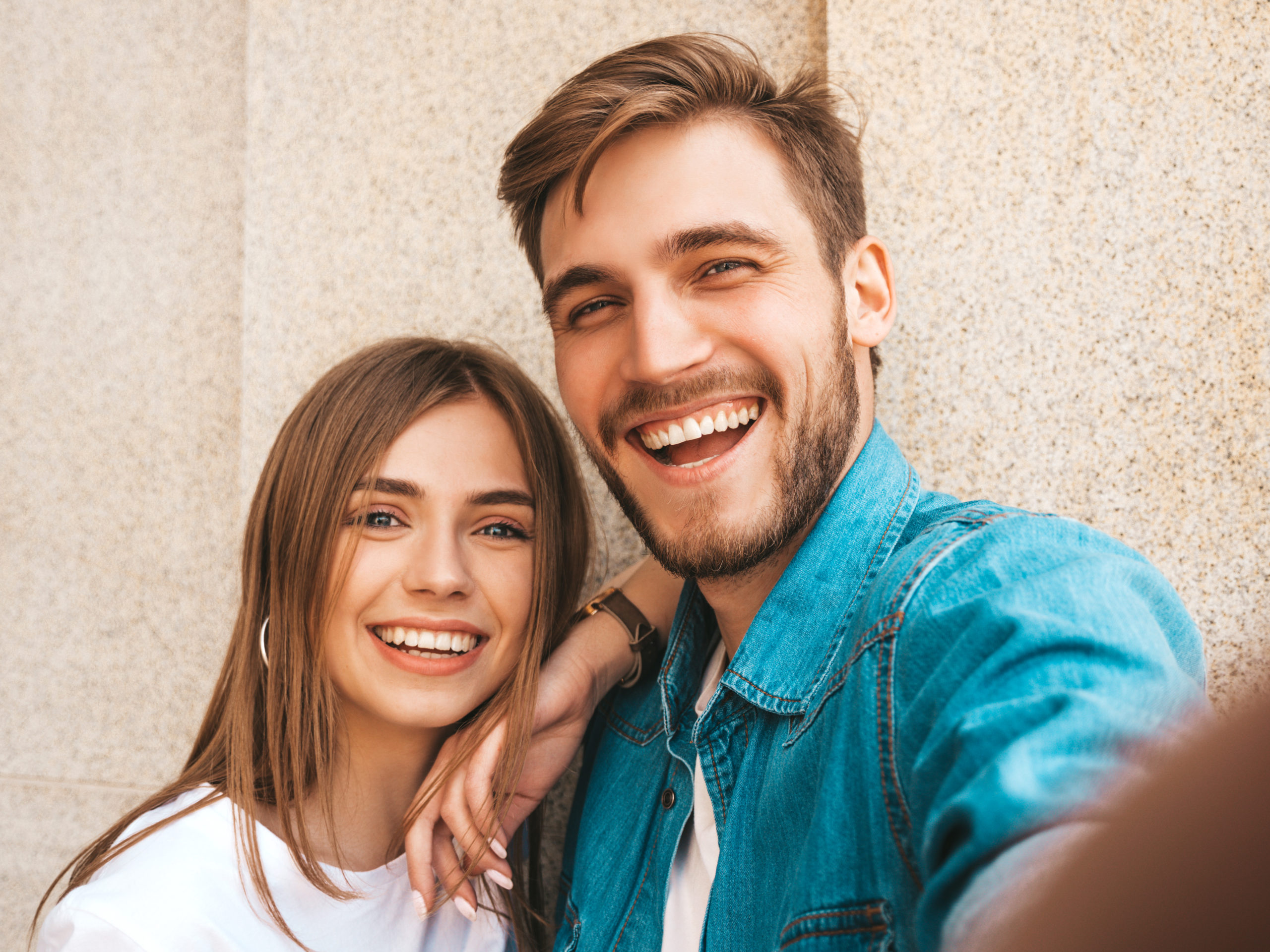 Smiling beautiful girl and her handsome boyfriend in casual summer clothes. Happy family taking selfie self portrait of themselves on smartphone camera. Having fun on the street background Smiling beautiful girl and her handsome boyfriend in casual summer clothes. Happy family taking selfie self portrait of themselves on smartphone camera. Having fun on the street background